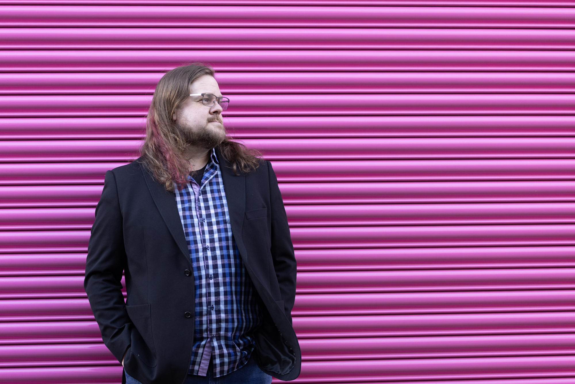Steve Ross standing in front of a pink shopfront shutter.