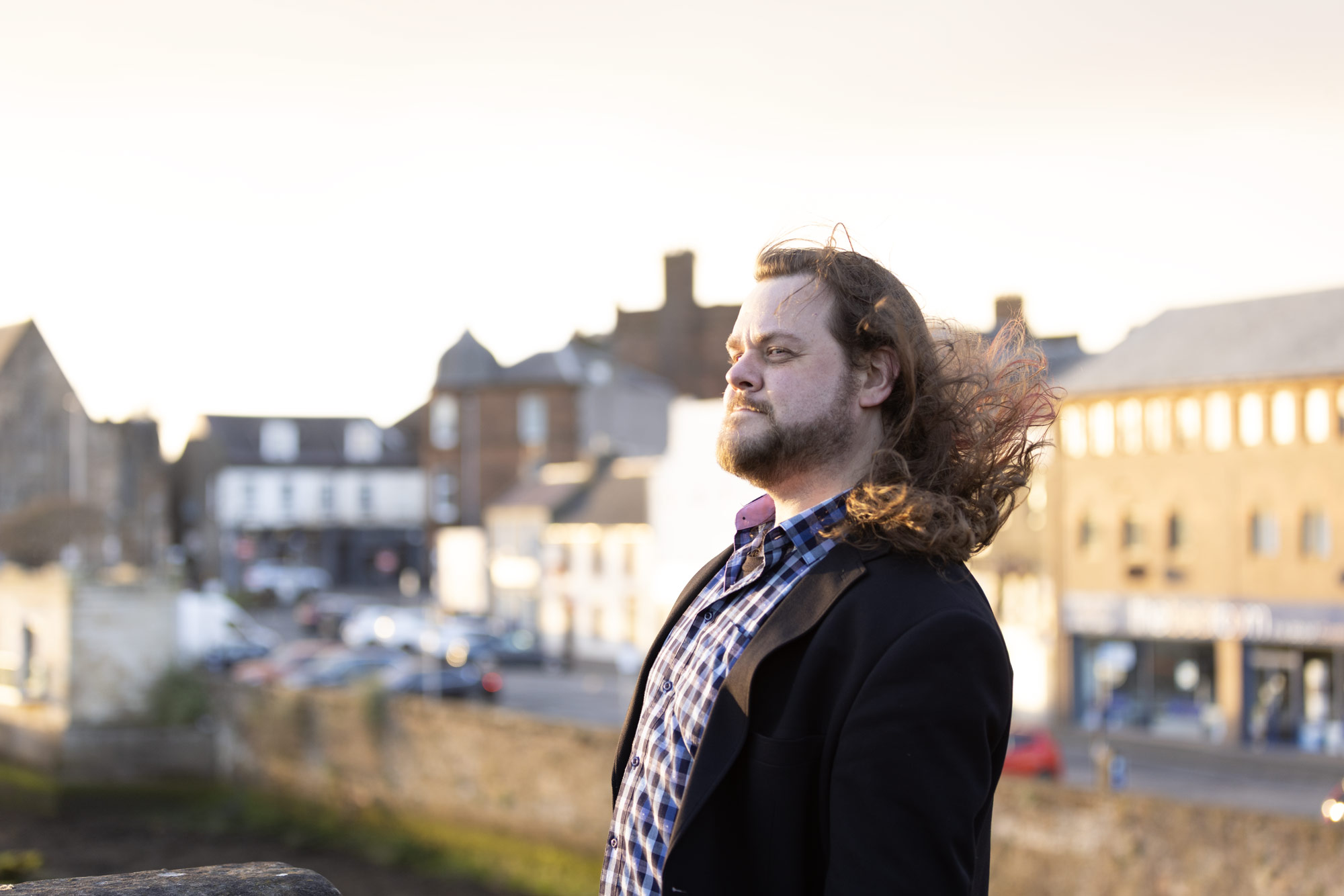 Steve Ross standing on an old stone bridge overlooking the river and Ayr Town Centre